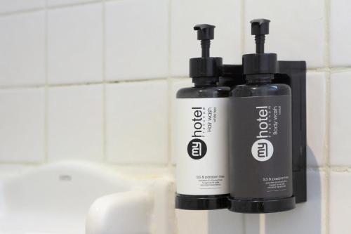 two bottles ofodorizers sitting on a bathroom sink at My Hotel Pratunam in Bangkok