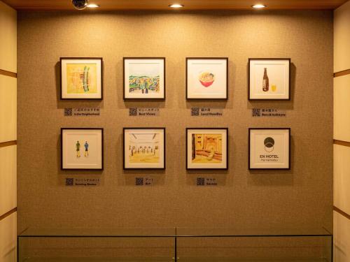 a wall with framed pictures on a wall at EN HOTEL Hamamatsu in Hamamatsu
