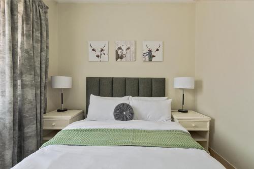 a bedroom with a bed with two night stands and two lamps at Calmwood Stay in Midrand