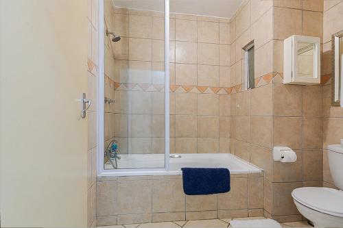a bathroom with a shower and a tub and a toilet at Calmwood Stay in Midrand