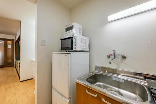 a kitchen with a microwave on top of a refrigerator at YAGARA TERRACE HOUSE OSAKA Room B in Osaka