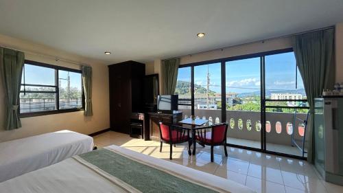 a hotel room with a bed and a table with a view at Surin Sunset Hotel - SHA in Surin Beach