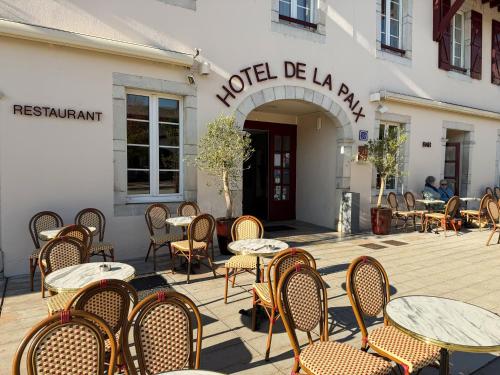 a row of tables and chairs in front of a building at Hôtel-Restaurant de La Paix in Saint-Palais