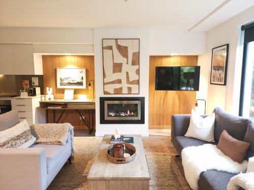 a living room with two couches and a fireplace at Hygge Garden Apartment in Queenstown