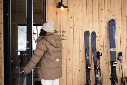 a person is standing next to a wall with skis at Auberge Sondre in Asahikawa