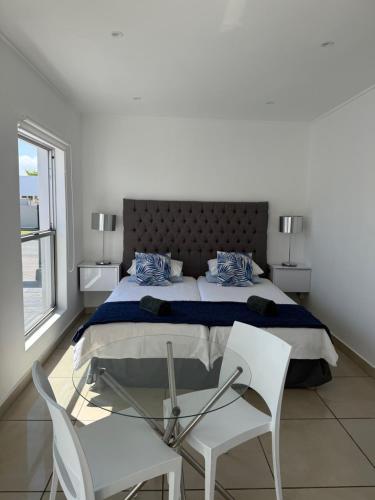 a bedroom with a bed and two white chairs at Studio on Main in Langebaan