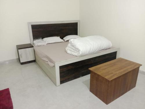 a bedroom with a bed with white sheets and a table at Sparsh Inn Hotel & Geust House in Gorakhpur