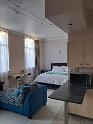 a bedroom with a bed and a blue couch in a room at Mapungubwe hotel unit 525 in Johannesburg