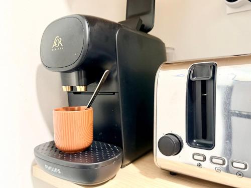 a coffee maker with a cup next to a toaster at La perle suedoise - Studio avec terrasse et cour privée in Calais