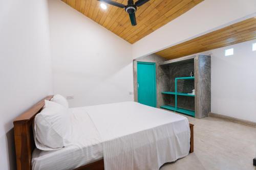 a bedroom with a white bed and a blue door at Villa Pigeon Paradise in Unawatuna