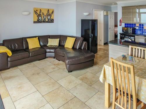 a living room with a brown leather couch and a kitchen at Pendine Beach Apartment in Pendine