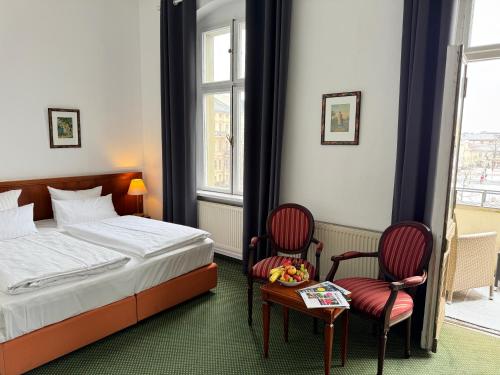 a hotel room with a bed and two chairs at Hotel am Luisenplatz in Potsdam