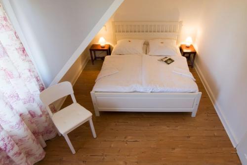 a bedroom with a white bed and a chair at Clara Elisabeth in Döhnsdorf