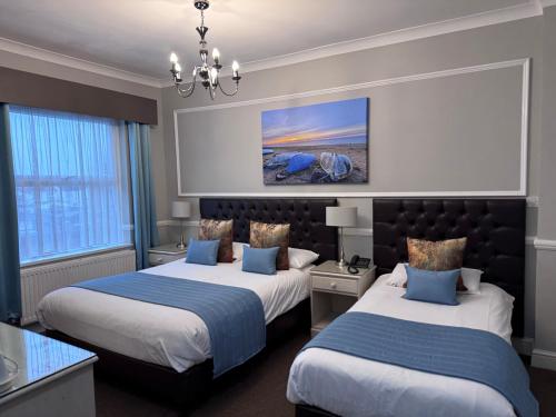 a hotel room with two beds and a chandelier at Camelia Hotel in Southend-on-Sea