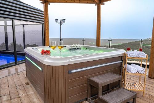 a hot tub with two glasses of wine at Wood & Soul - בקתות משולשות מיוחדות עם בריכה פרטית in ‘Isfiyā