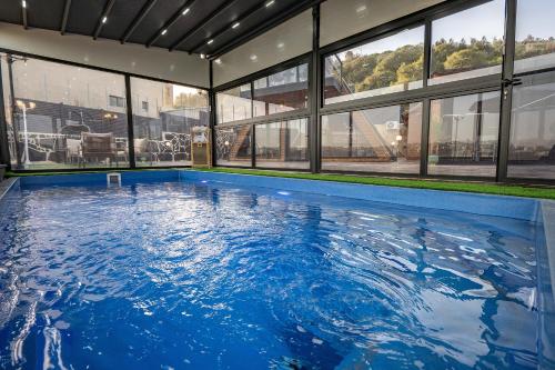 a large swimming pool in a building with windows at Wood & Soul - בקתות משולשות מיוחדות עם בריכה פרטית in ‘Isfiyā