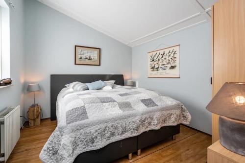 a bedroom with a bed with a gray and white comforter at Christoffellaan 57 in Brouwershaven