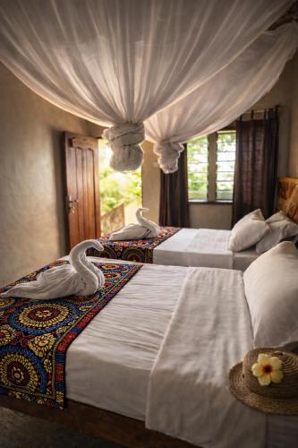 a bedroom with two beds with white sheets and a window at Voyager's Center in Kikorongo