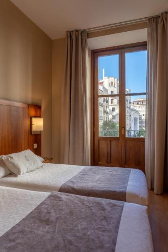a bedroom with a large bed and a large window at Ateneo Puerta del Sol in Madrid