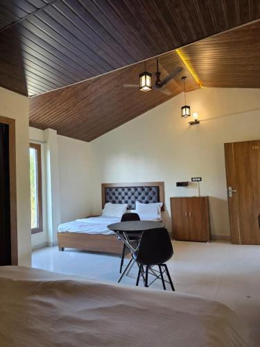 a bedroom with a bed and a table with two chairs at The Jungle Castle Resort in Rāmnagar