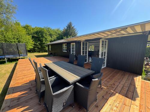 a patio with a table and chairs on a deck at Renoveret sommerhus nær fjord - Stor terrasse, have & plads til 7 gæster in Kyndeløse