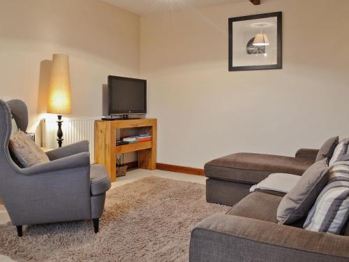 a living room with two couches and a flat screen tv at Dairy Cottage in Marros