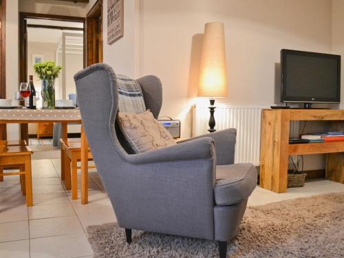 a living room with a chair and a television at Dairy Cottage in Marros
