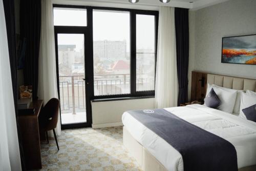 una camera d'albergo con un letto e una grande finestra di Cosmopolitan Hotel a Shymkent