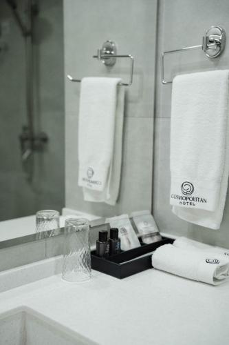 a bathroom with a sink and a mirror and towels at Cosmopolitan Hotel in Shymkent