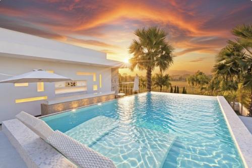 a swimming pool with two chairs and a villa at Palm Villa - Award Winning Modern Luxury & Exclusive Villa in Chiang Mai