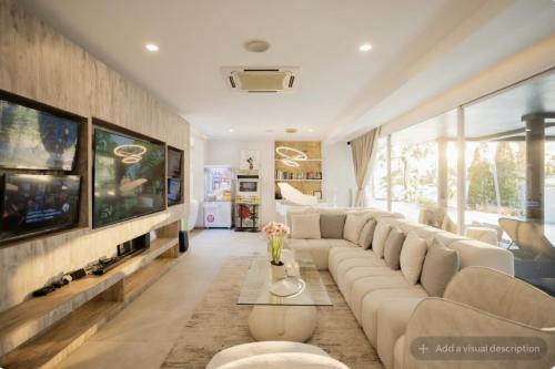 a living room with a large couch and a tv at Palm Villa - Award Winning Modern Luxury & Exclusive Villa in Chiang Mai