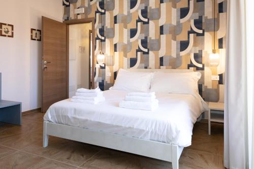 a white bed in a room with a wall at Guest house - L'amante e il marinaio in Fiumicino