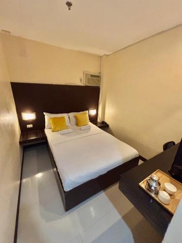ein Schlafzimmer mit einem Bett mit gelben Kissen und einem Tisch in der Unterkunft Anton's Inn in Balanga