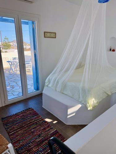 a bedroom with a bed with a mosquito net at Peaceful Cycladic Studio with Large Terrace & View in Tripiti