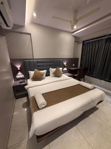 a bedroom with a large bed and a table at Hotel Kurla Suites in Mumbai