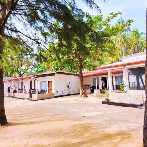 a building with trees in front of it at French garden Pragash Beach Hotel in Trincomalee