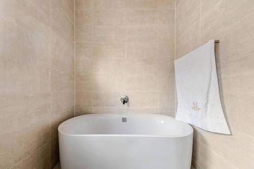 a white tub in a bathroom with a towel on the wall at 2 Bedroom 2 Bathroom Executive Suite in Midrand