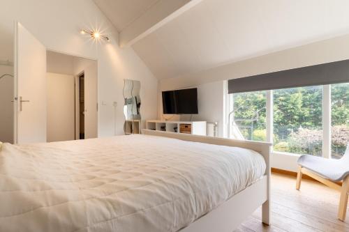 a white bedroom with a large bed and a window at Villa Beach & Spa in Julianadorp