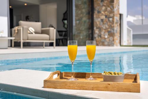 two champagne glasses on a tray next to a swimming pool at Villa Palmera in San Javier