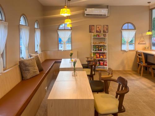 a room with a table and chairs and windows at Baan Mak Mai Hotel in Si Sa Ket