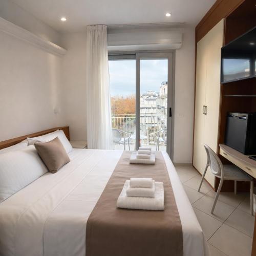 a bedroom with a large bed with a desk and a balcony at Hotel Regal in Rimini