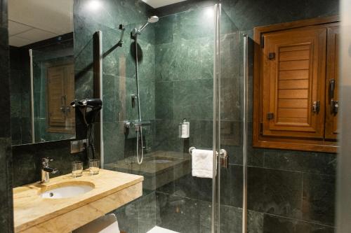 a bathroom with a sink and a glass shower at León Center Rooms in León