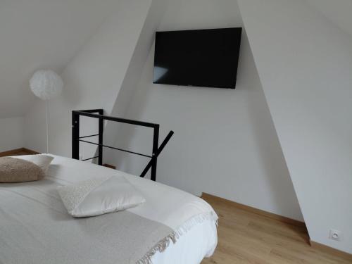 a bedroom with a bed with a tv on the wall at Cozyhouse in Touquet Berthe