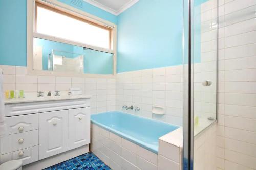 a bathroom with a blue tub and a shower at Hampton Beach House in Melbourne