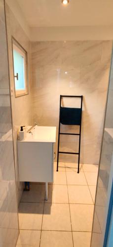 une salle de bain avec un lavabo blanc et une chaise dans l'établissement Le scandinave, à Douai