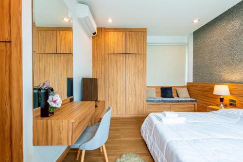 a bedroom with a bed and a desk with a television at TheH Pool Villa in Nong Prue