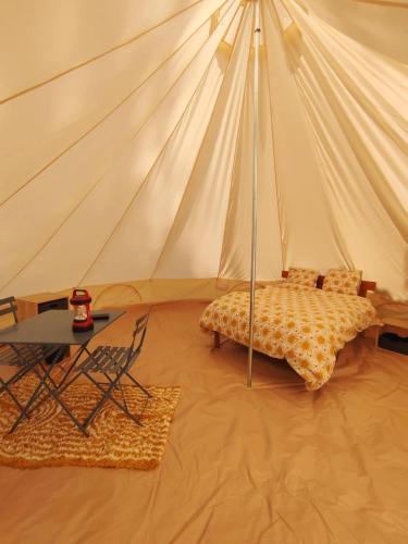 a tent with a bed and a table in a room at Chez Tombivouac in Pierrefonds