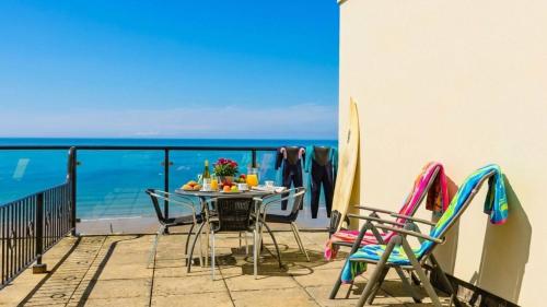a table and chairs on a balcony with the ocean at PUTSBOROUGH CLIFTON COURT 17 1 Bedroom in Croyde