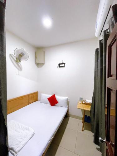 a small room with a bed with a red pillow at Marine Hotel & Apartment in Vung Tau