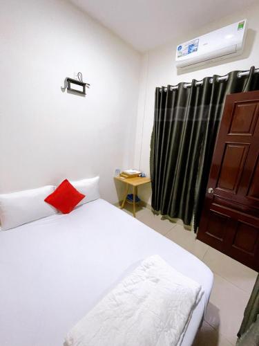a bedroom with a bed with a red pillow and a window at Marine Hotel & Apartment in Vung Tau